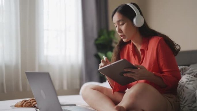 亚洲女人在卧室用笔记本电脑进行视频会议聊天