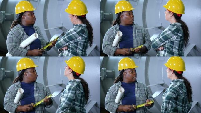 Two women working in metal fabrication plant, talk