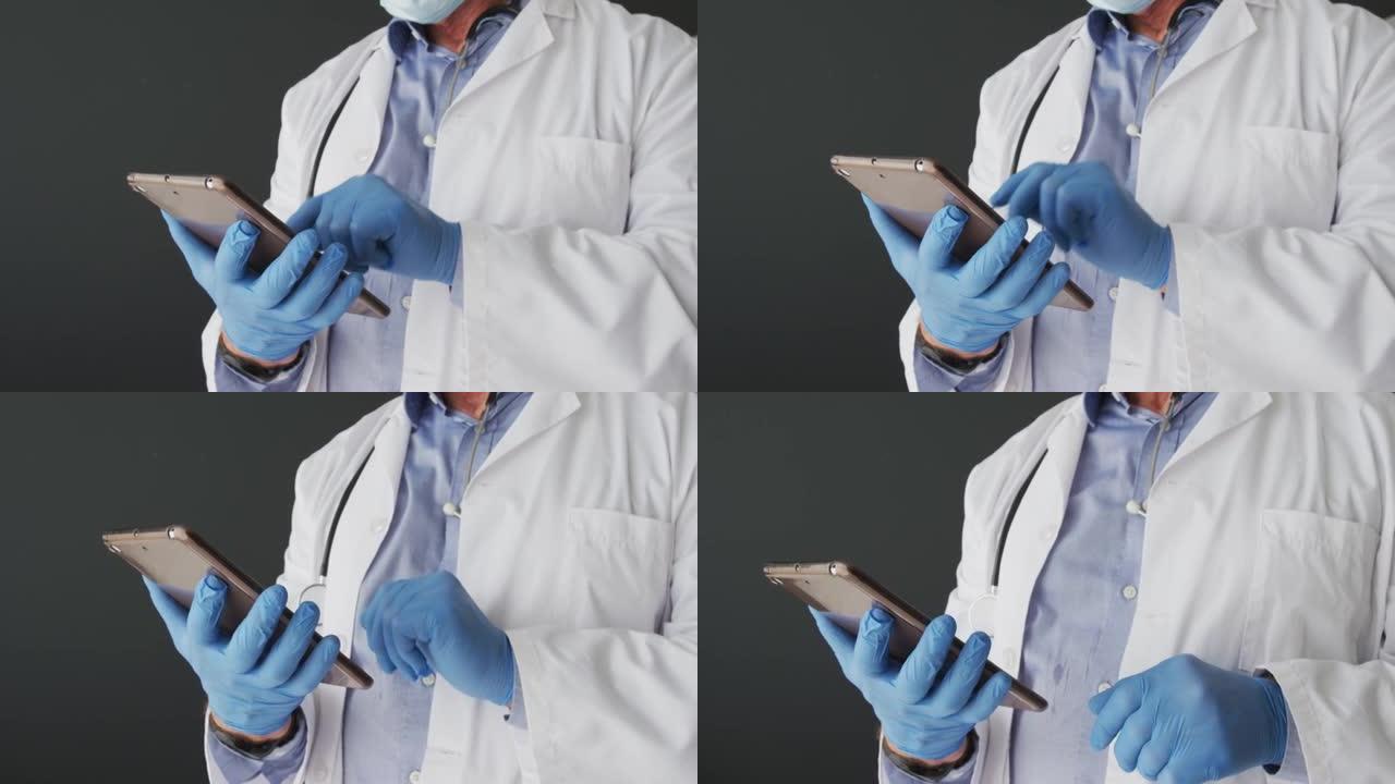使用数字平板电脑戴着手术手套的高加索男性医生的中段