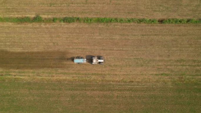 空中，自上而下: 拖拉机水箱在干旱的耕地上喷洒粪便