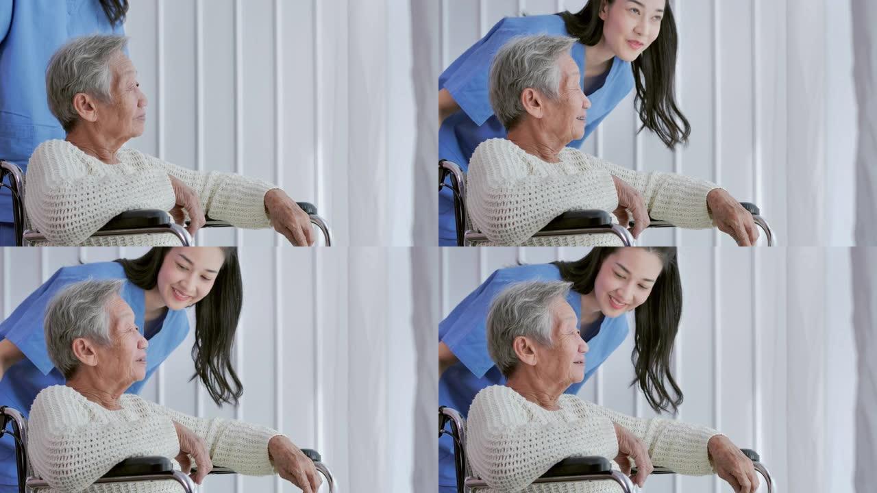 亚洲老年妇女坐在轮椅上，在家或医院靠窗与亚洲年轻女护士医生交谈。老年祖母倾听护理人员给予支持，老年人