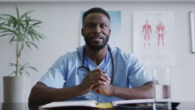 非裔美国男性医生在视频通话咨询期间在办公桌上交谈和打手势