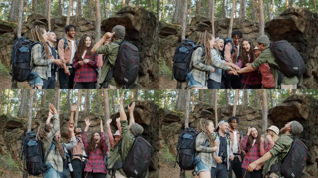 一群朋友游客聊天，然后携手表达团结和团结站在森林里
