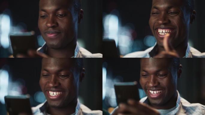 快乐的黑人在黑暗舒适的房间里浏览有趣的在线内容或在社交媒体上使用智能手机与朋友聊天。男性坐在互联网上