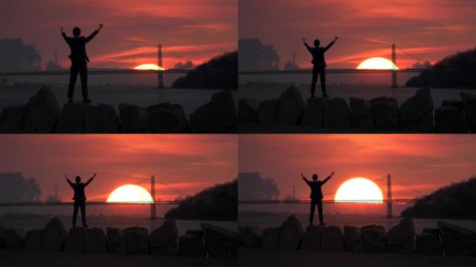 一名男子站在户外，双臂举起，做着胜利的姿势，在早晨的日出中展示了成功的生活方式