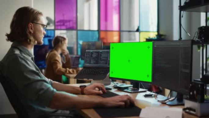男性程序员编写代码，并使用台式计算机，在现代办公室中展示绿屏Chromakey。高加索人致力于创新数