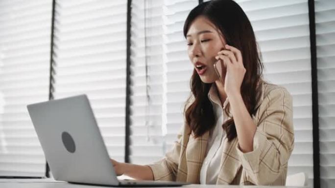女商人在办公室使用笔记本电脑在电话上聊天