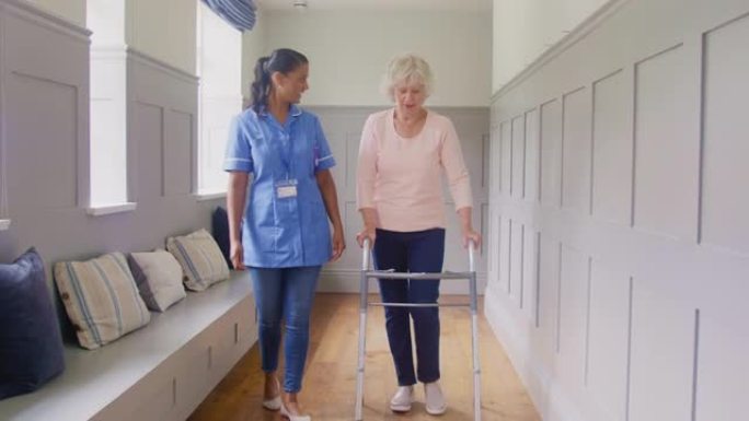 穿着制服的女护理人员在家里使用步行架的高级妇女