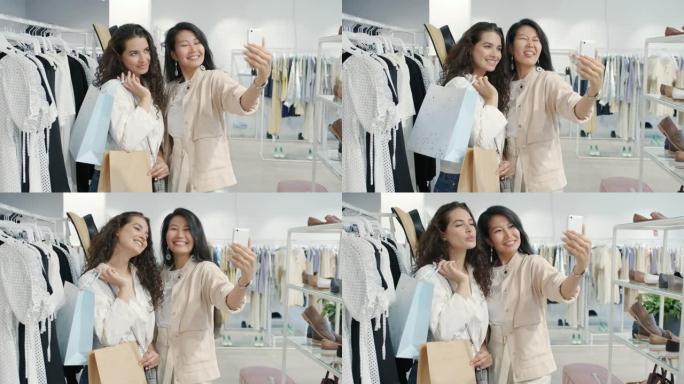 亚洲和高加索女性朋友在服装店用智能手机相机拿着包自拍