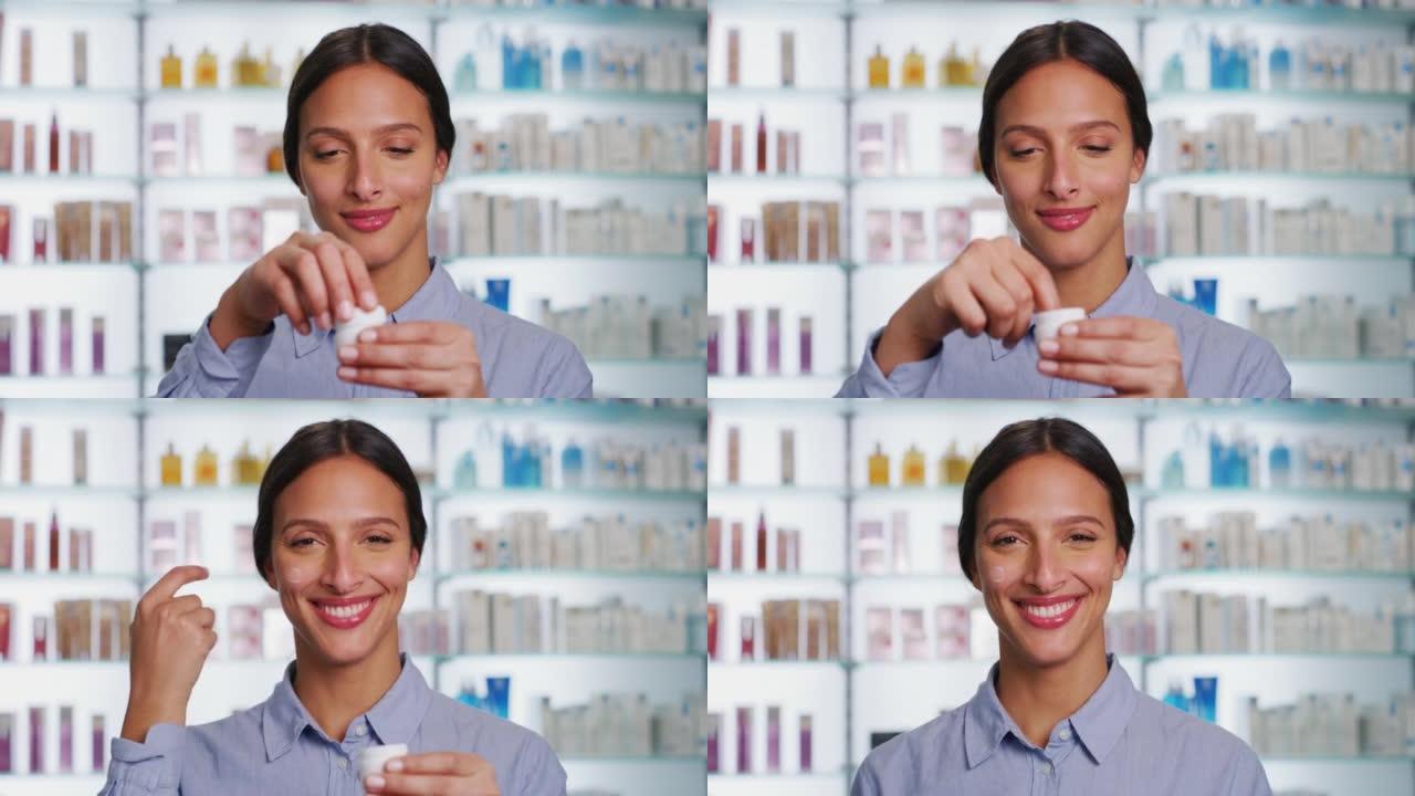 一个拥有完美皮肤的年轻女子正在上面涂上奶油，并在药房背景下的相机中微笑。