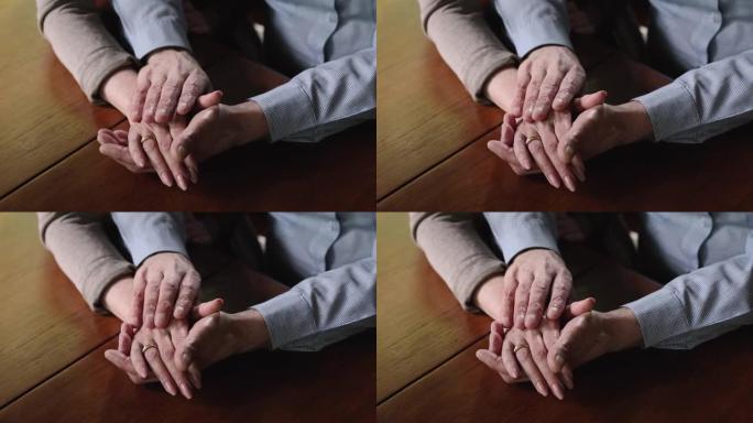 关闭年迈的丈夫抚摸皱纹的手或成熟的妻子。