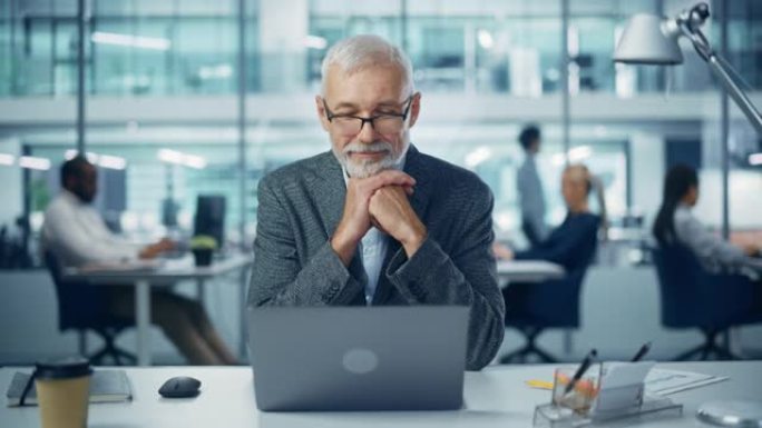 现代办公室: 成功的中年大胡子商人在办公桌前的笔记本电脑上工作的肖像。微笑的企业工人。拥有快乐专业人