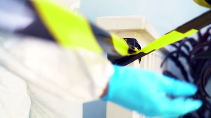 穿着PPE套装的慢动作医务人员在新型冠状病毒肺炎感染冠状病毒的患者家中用黄色警告带为隔离和检疫区域设