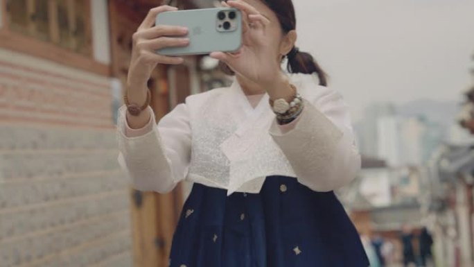 年轻的亚洲女性在韩国旅行时使用智能手机拍照。