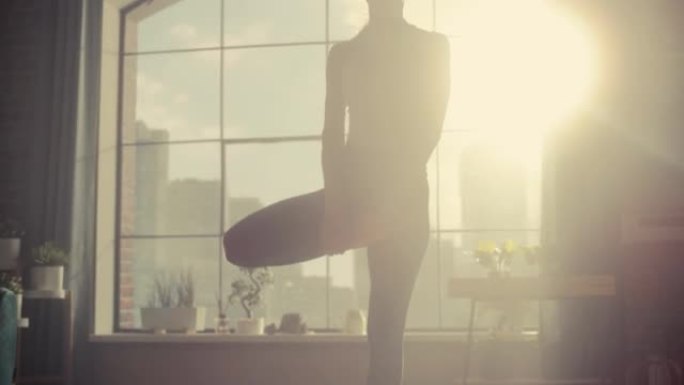 年轻美丽的女性锻炼身体，在树木瑜伽中保持平衡，早上在她阳光明媚的阁楼公寓里摆姿势。健康的生活方式、健