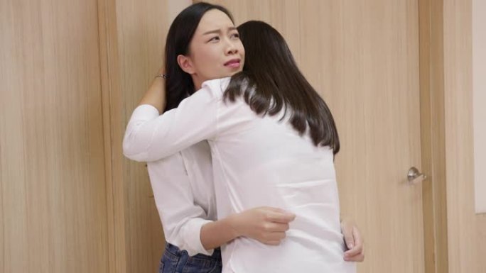 两个年轻的亚洲妇女，姐妹或朋友在病房或走廊医院前一起感到悲伤的同理心。父母生病的烦恼情绪，没有准备好