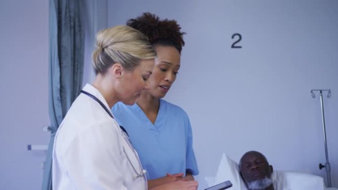 多元化的女医生在医院病床上看着站在病人附近的平板电脑