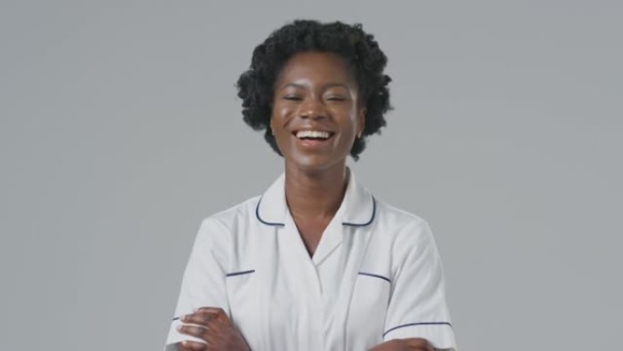 在朴素背景下穿着制服的笑笑女护士的工作室肖像