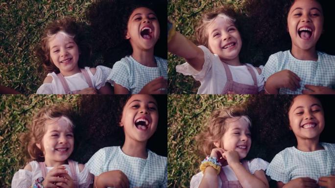 两个快乐的小女孩躺在草地上微笑着被挠痒痒