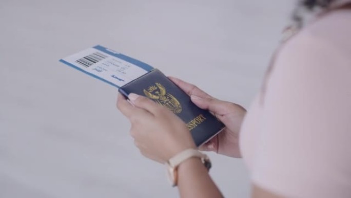 站在机场的旅客机票和护照的特写镜头。女乘客手持旅行和身份证件准备登机，等待国际离境