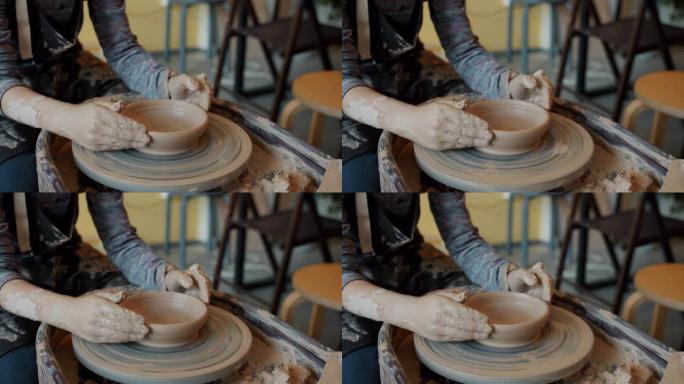 儿童脏手的慢动作特写从陶轮上的粘土上塑造碗
