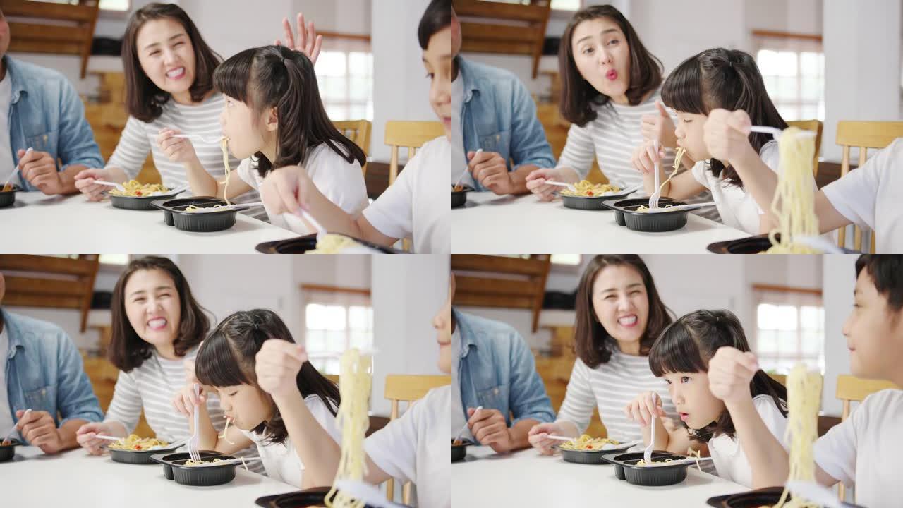 快乐快乐的亚洲家庭吃午餐在现代家庭的餐厅里用塑料容器吃意大利面条。