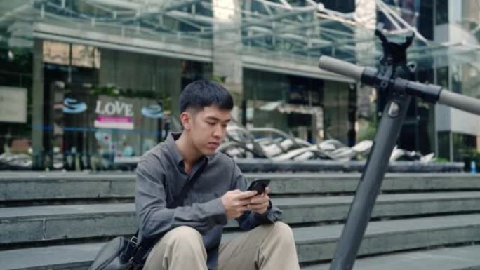 亚洲男子使用手机应用解锁电动推踏板车，用于城市旅行通勤。