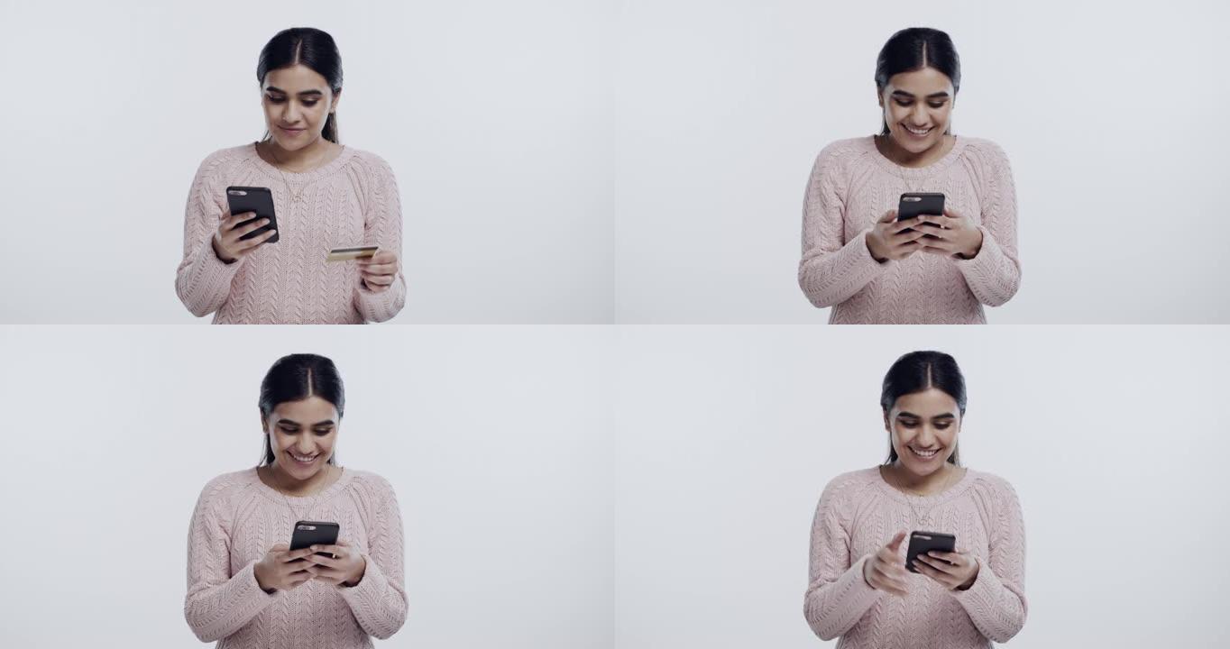 4k视频片段，一名年轻女子独自站在演播室并使用手机进行在线购物