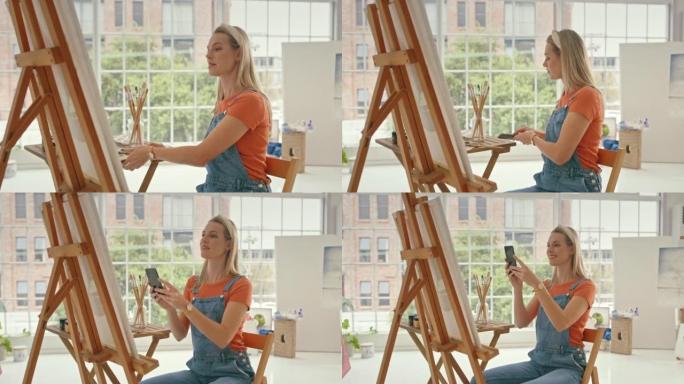 女画家用手机为社交媒体拍摄了一幅画的照片，以添加到她在工作室的作品集中。艺术家为她在画布上画的图画拍