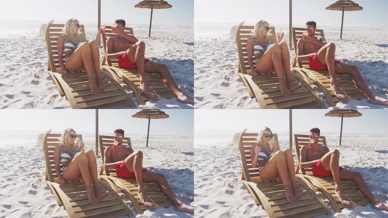 白人夫妇坐在沙滩上的日光浴床上