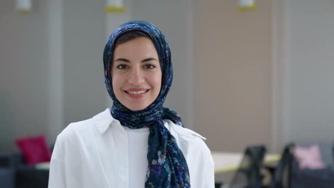 一名戴着头巾的中东妇女的肖像站在她的办公室里