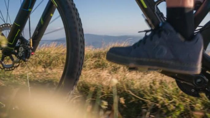 越野骑自行车的人在阳光照射下爬上风景秀丽的山道的细节
