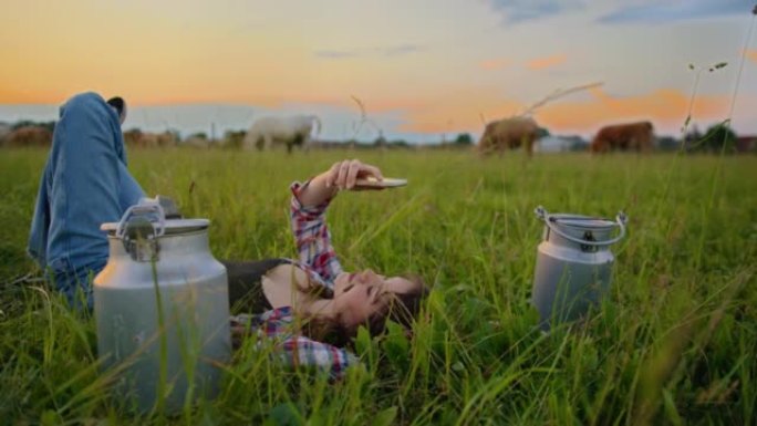 SLO MO Young女牧场主躺在牧场中间的草地上时使用智能手机