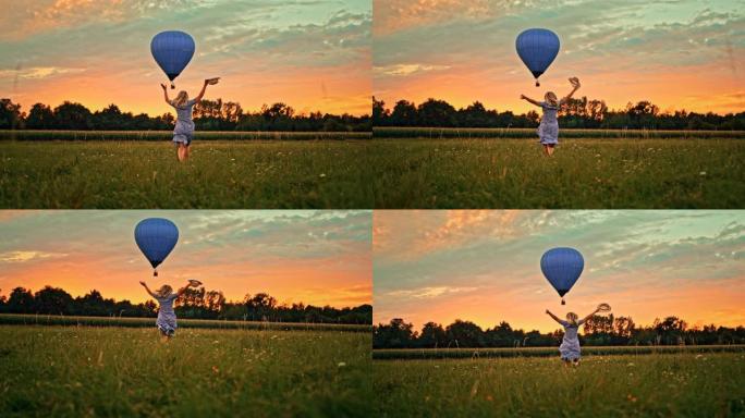 超级慢动作女人在草地上奔跑，朝着飞舞的热气球挥手