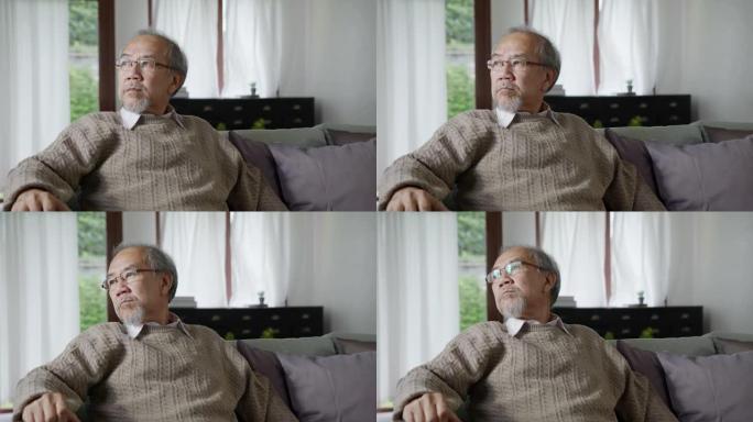 中景:亚洲老年男性或抑郁的爷爷在养老院的客厅里对着隔离区望着窗外，感觉悲伤，思念，不快乐，体贴，在精