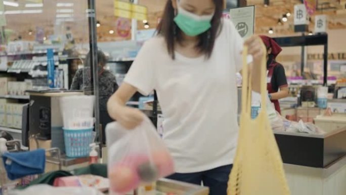 亚洲妇女在无废物商店包装可重复使用的购物袋