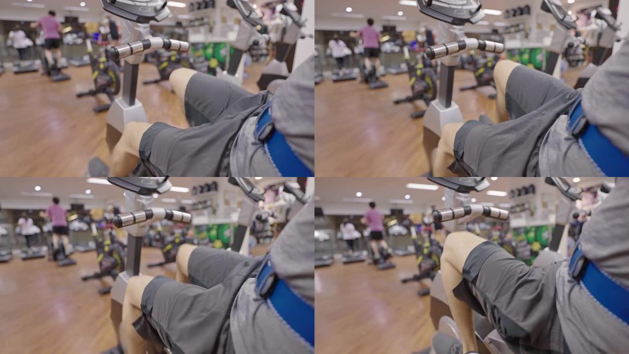 男子腿在健身房骑健身车。