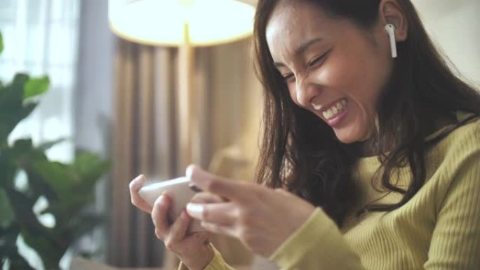 亚洲女性在客厅玩智能手机数码小工具在线游戏
