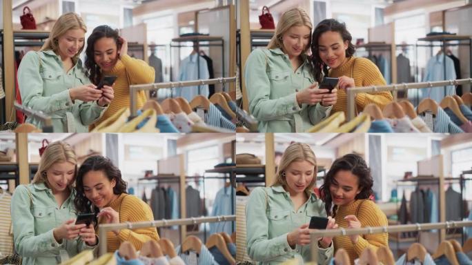 两个漂亮的女性朋友在服装店购物，使用智能手机，在线浏览，在互联网上比较。顾客选择衣服。时尚的商店，多