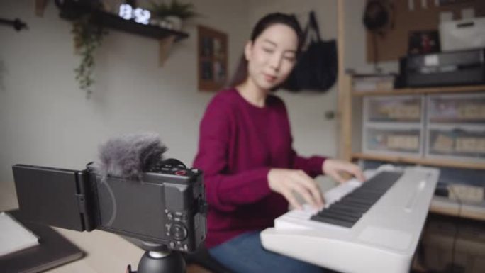 家庭独自键盘钢琴爱好年轻女子用智能手机练习钢琴