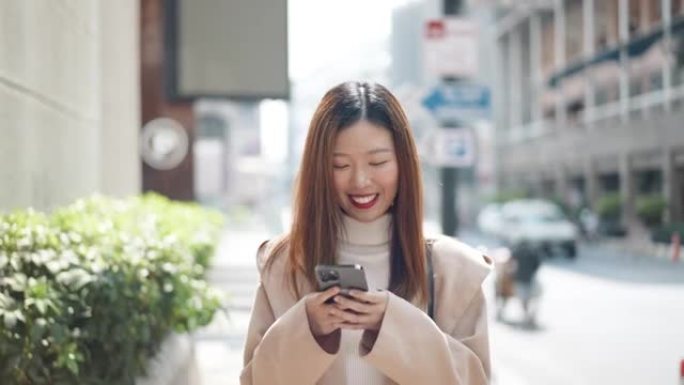 亚洲妇女在城市使用智能手机行走
