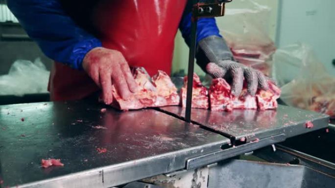 肉类加工厂，食品生产设施。工厂员工正在使用一种用肉切骨头的机制