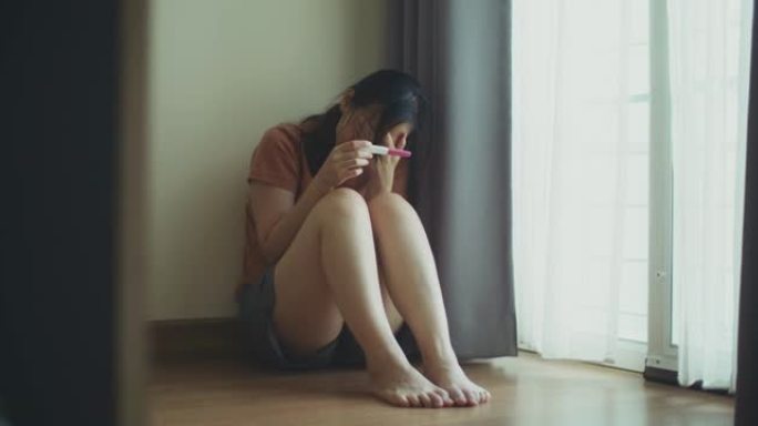 悲伤的年轻女子在家里接受怀孕测试后看起来很沮丧
