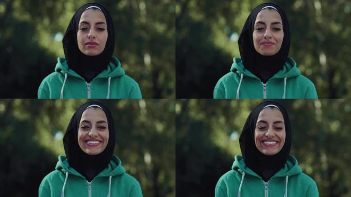 美丽的年轻阿拉伯女子微笑着绿色背景的肖像。带着头巾的快乐穆斯林女少年在公园享受新鲜空气，利用周末的空