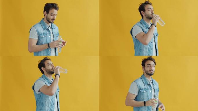 阿拉伯年轻人喝水并在黄色背景上看着相机的慢动作肖像