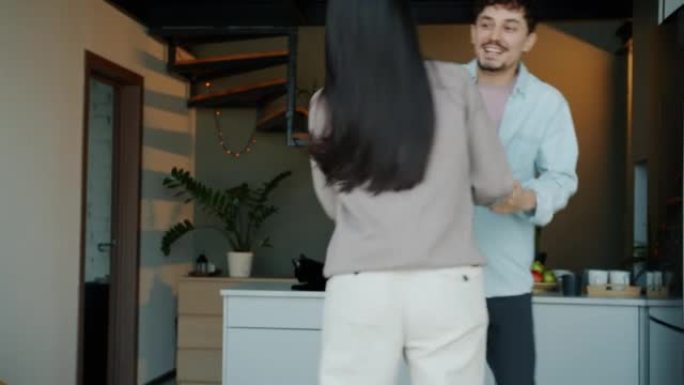 亚洲女子和混血儿男子在现代厨房跳舞和玩乐