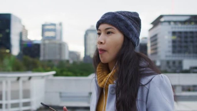 亚洲妇女使用智能手机走路并吃三明治