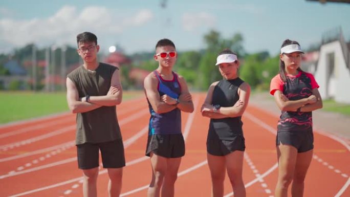 亚洲中国自信运动员运动队以冷静的态度看着镜头，早上站在全天候的田径体育场上