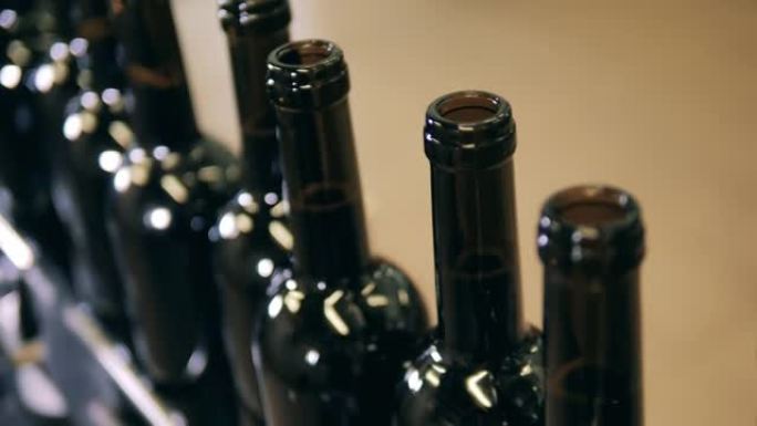 装满的酒瓶在生产线上移动的特写镜头。葡萄酒生产设施。