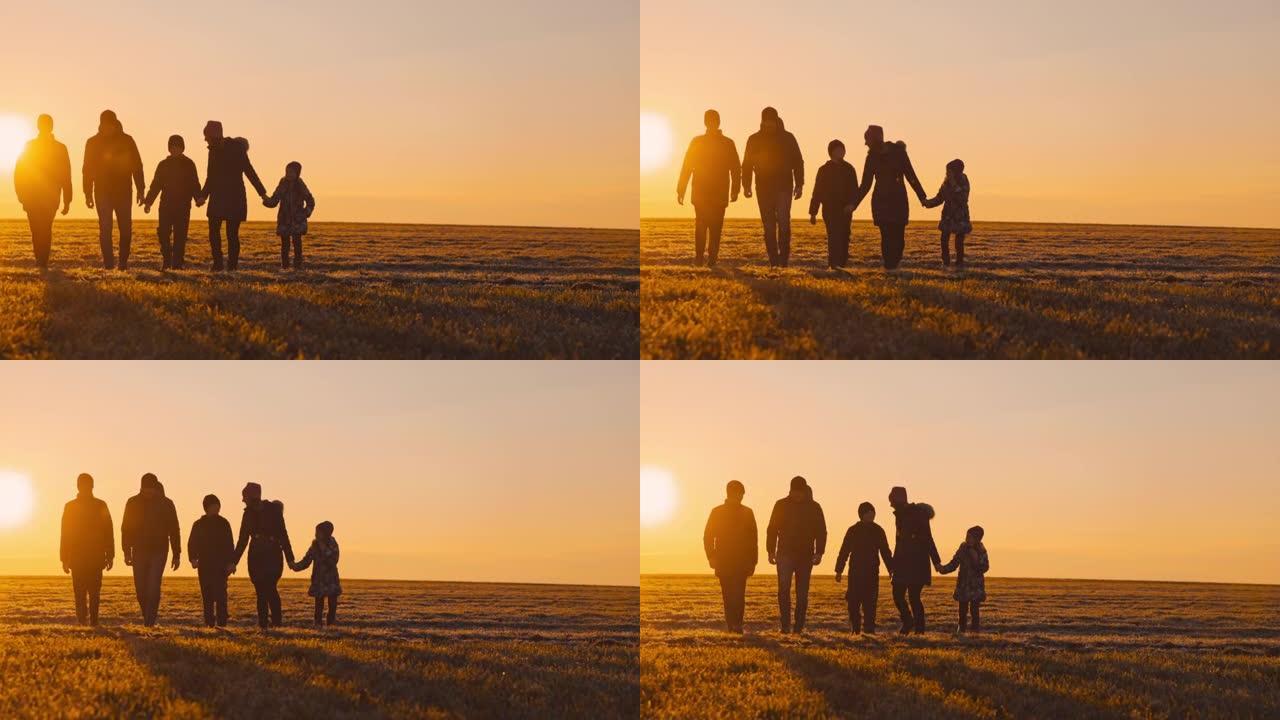 日落时，有三个孩子的SLO MO WS家庭在草地上散步